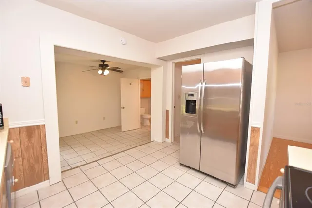 a view of a refrigerator in kitchen and an empty room