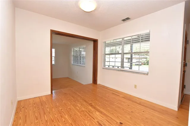 a view of an empty room with wooden floor and a window