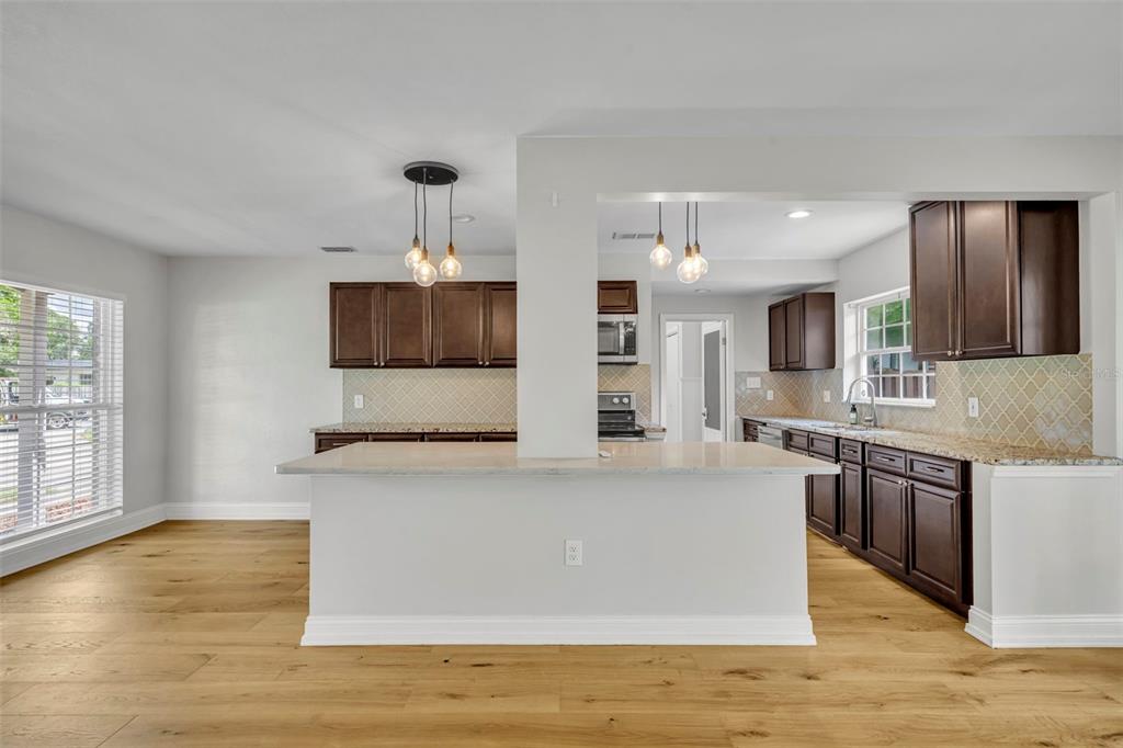4234 Kendrick Road Orlando, FL 32804 - Photo 8 of 46 a large kitchen with stainless steel appliances granite countertop a large stove a sink dishwasher and a microwave oven with large wooden cabinets