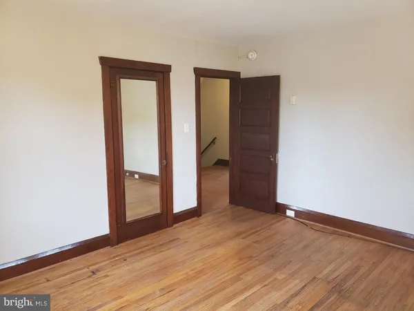a view of an empty room with closet and wooden floor