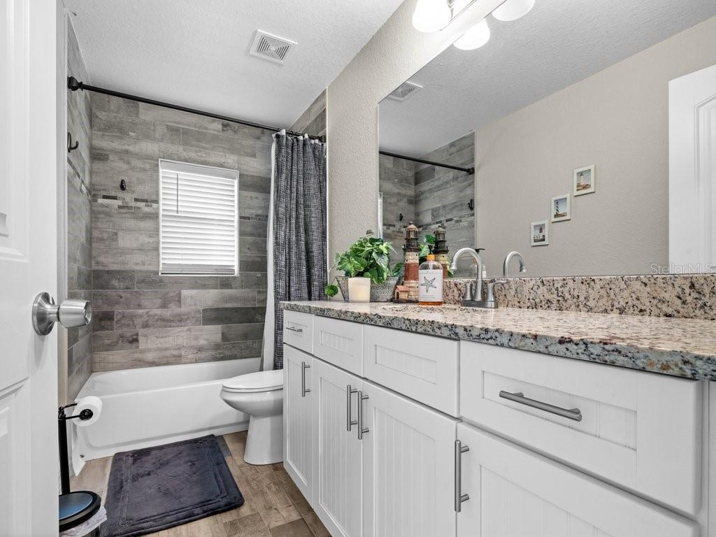 8221 Agate Street Port Charlotte, FL 33981 - Photo 36 of 50 a bathroom with a granite countertop sink a toilet a mirror and shower