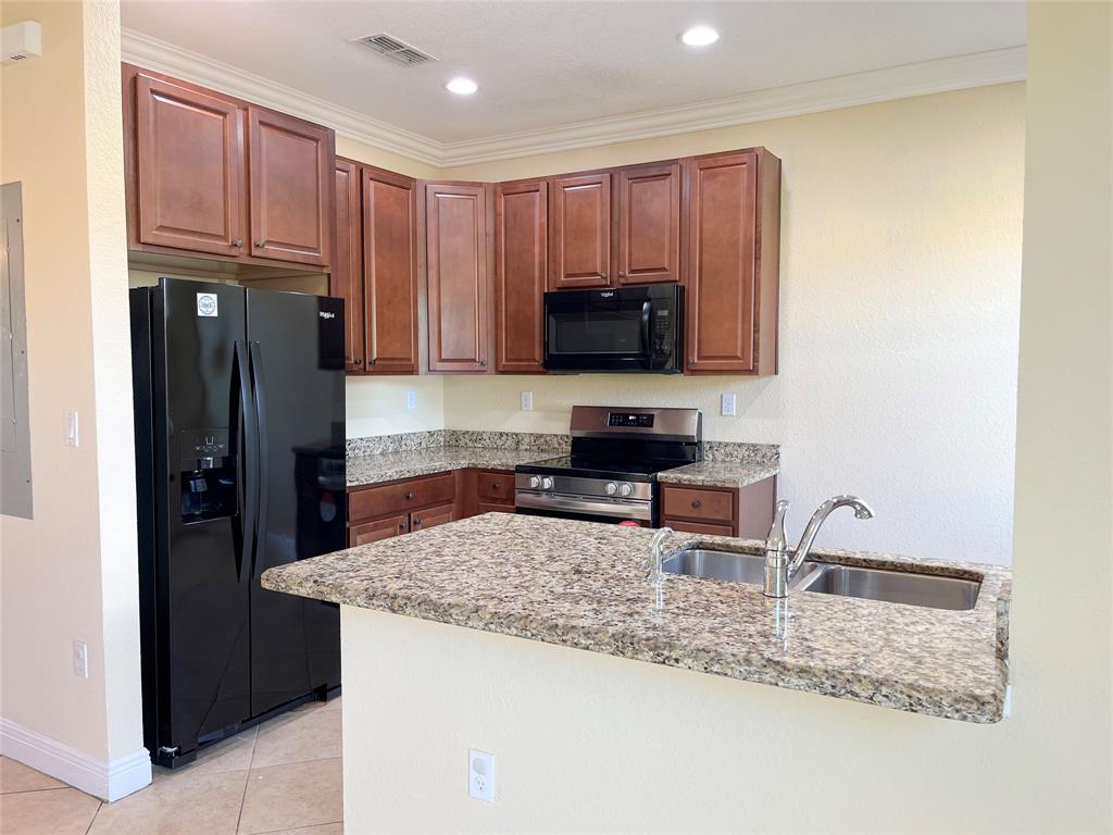 291 Lake Monterey Circle Boynton Beach, FL 33426 - Photo 9 of 47 a kitchen with granite countertop a refrigerator and a sink