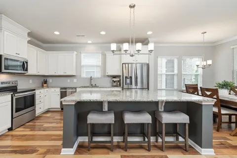 a kitchen with stainless steel appliances granite countertop a stove a microwave and a white cabinets