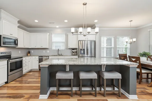 a kitchen with stainless steel appliances granite countertop a stove a microwave and a white cabinets