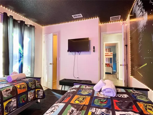 a bedroom with bed and a flat tv screen on a dresser