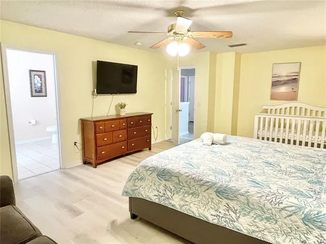 a bedroom with a bed a flat screen tv and a chandelier