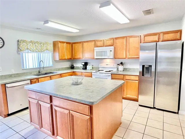 a kitchen with stainless steel appliances granite countertop a sink a refrigerator and a counter space