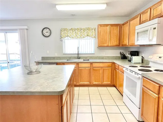 a kitchen with a sink a stove top oven cabinets and a window