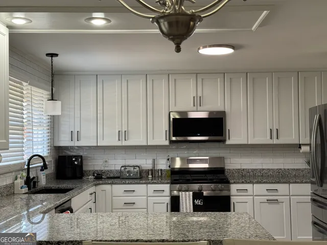 a kitchen with stainless steel appliances granite countertop a stove a sink a microwave a refrigerator and cabinets