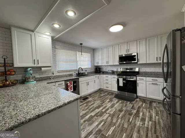 a kitchen with stainless steel appliances granite countertop a sink stove and refrigerator