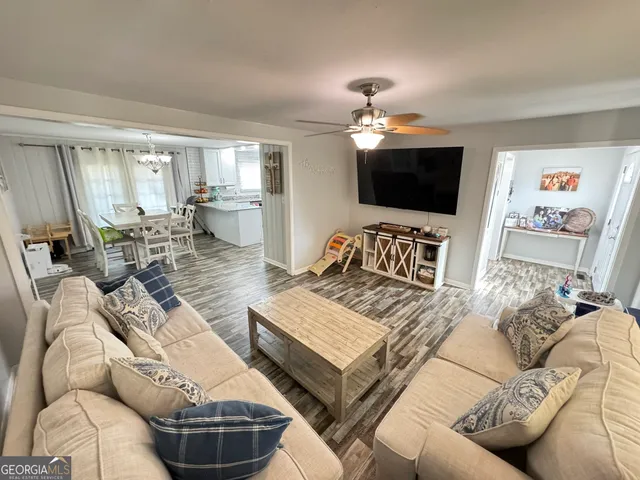 a living room with furniture a flat screen tv and kitchen view