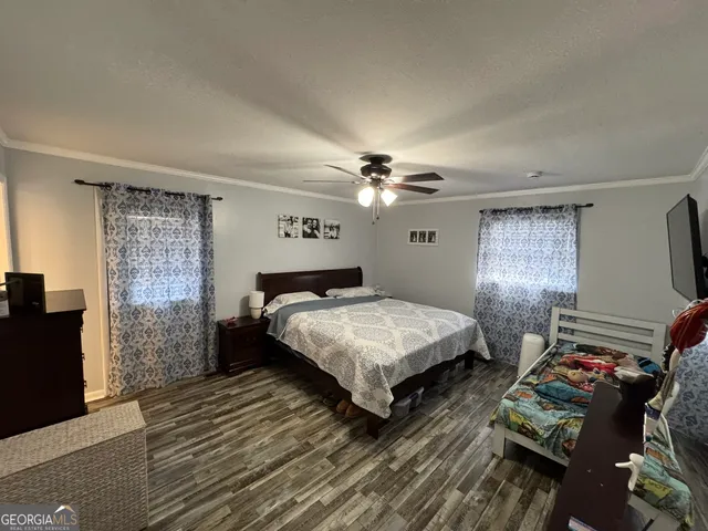 a bedroom with a bed dresser and wooden floor