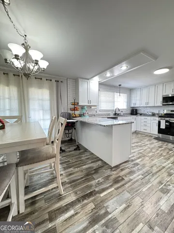 a kitchen with stainless steel appliances granite countertop a stove top oven a sink dishwasher and white cabinets with wooden floor