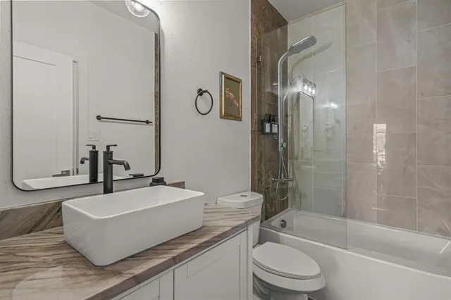 a bathroom with a bathtub shower sink mirror vanity and toilet
