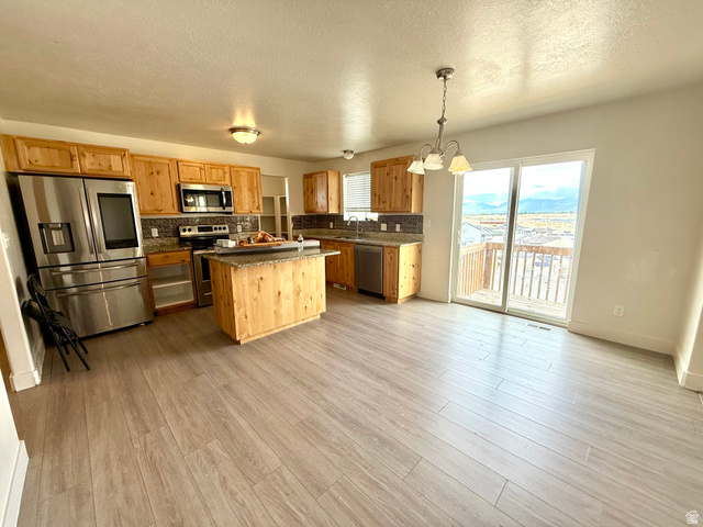 1823 South Longview Road Santaquin, UT 84655 - Photo 18 of 69 Kitchen featuring wood cabinetry, stainless steel appliances, a center island with countertop seating, and a stone-finish backsplash