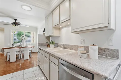 a kitchen with a sink dishwasher and white cabinets with wooden floor