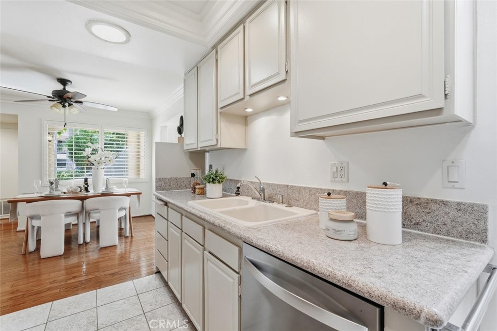 5512 West Paseo Del Lago, Unit C Laguna Woods, CA 92637 - Photo 12 of 45 a kitchen with a sink dishwasher and white cabinets with wooden floor