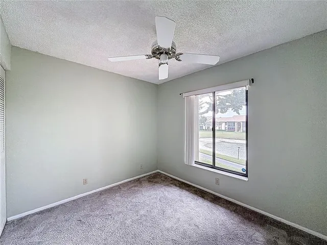 an empty room with a window and a fan