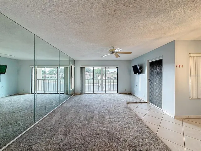 a view of a refrigerator in kitchen and an empty room with wooden floor