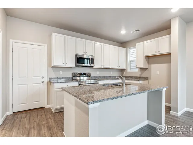 a kitchen with a sink a stove a microwave a center island and cabinets