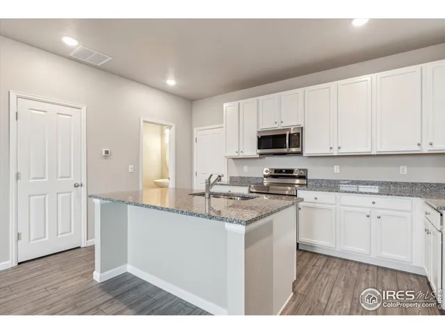 a kitchen with granite countertop a stove top oven a sink dishwasher and a microwave oven with white cabinets