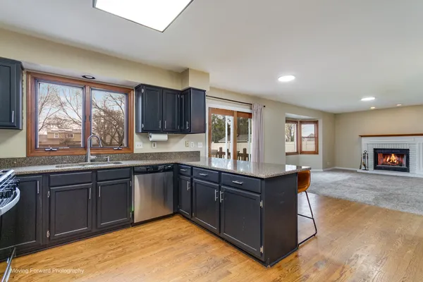 a kitchen with stainless steel appliances granite countertop wooden cabinets a sink dishwasher and a large window