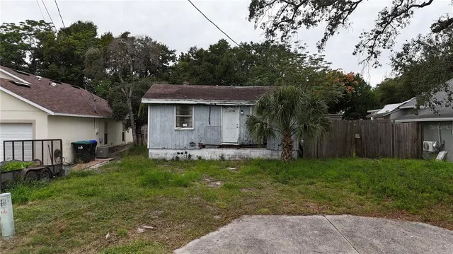 a backyard of a house with wooden fence and large trees