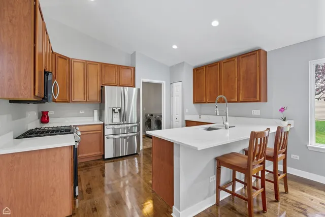 a kitchen with a refrigerator a stove top oven a sink dishwasher and wooden cabinets with wooden floor