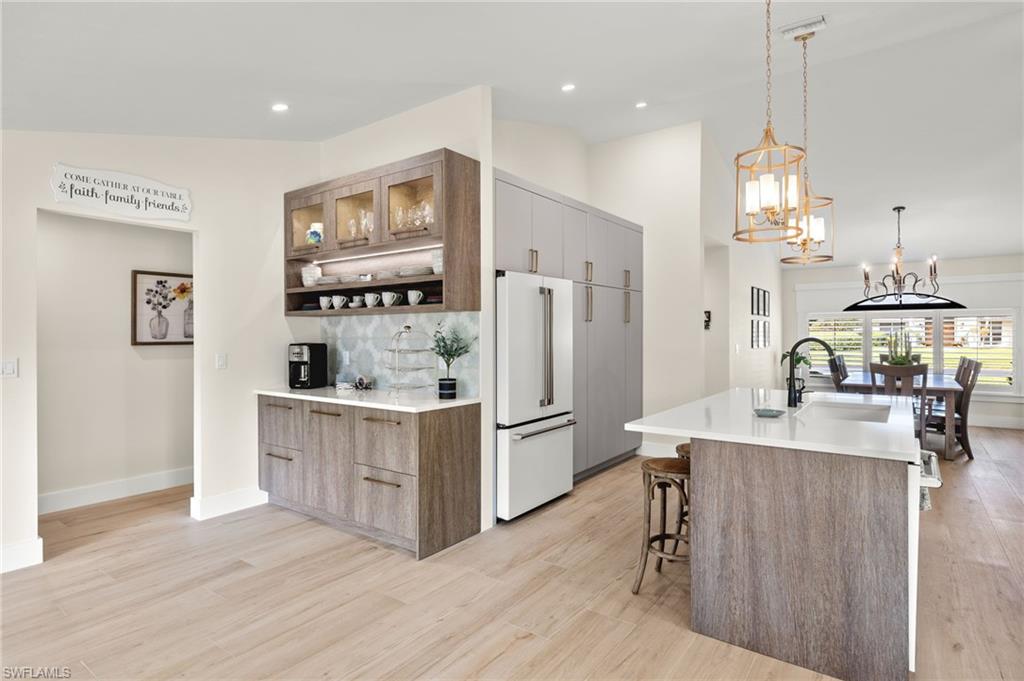10274 Boca Circle Naples, FL 34109 - Photo 9 of 26 a kitchen with white cabinets and stainless steel appliances