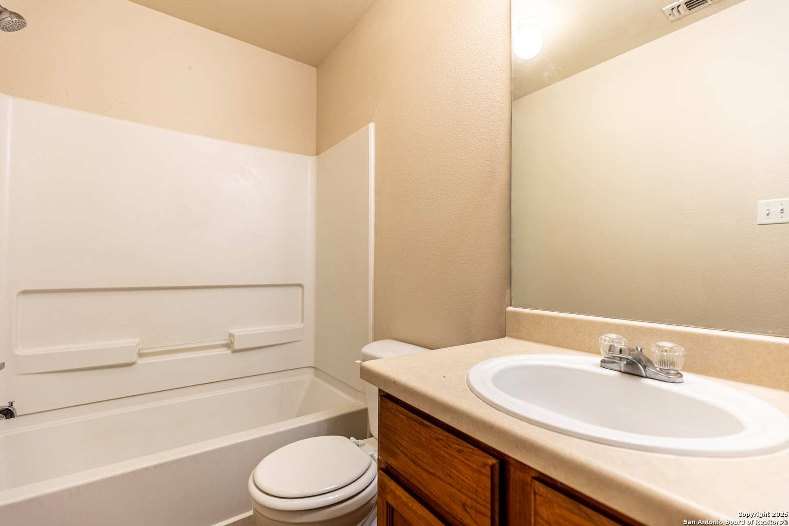 10711 Mathom Landing, Unit 1 Universal City, TX 78148 - Photo 24 of 31 a bathroom with a granite countertop sink toilet a mirror and shower