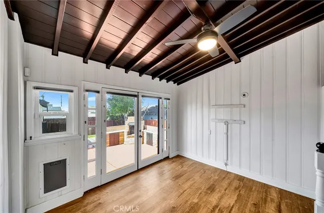 a view of an empty room with wooden floor and a kitchen