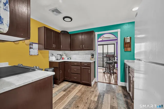 a kitchen with stainless steel appliances granite countertop a refrigerator a stove and a wooden floor