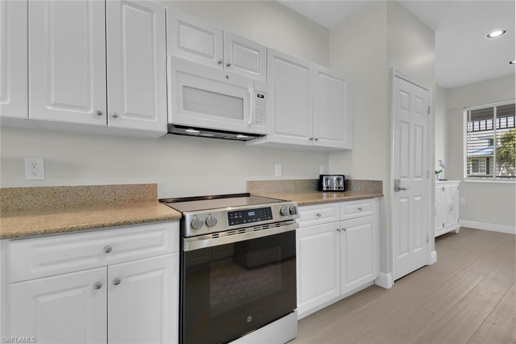 7925 Mahogany Run Lane, Unit 924 Naples, FL 34113 - Photo 13 of 40 a kitchen with granite countertop white cabinets and stainless steel appliances