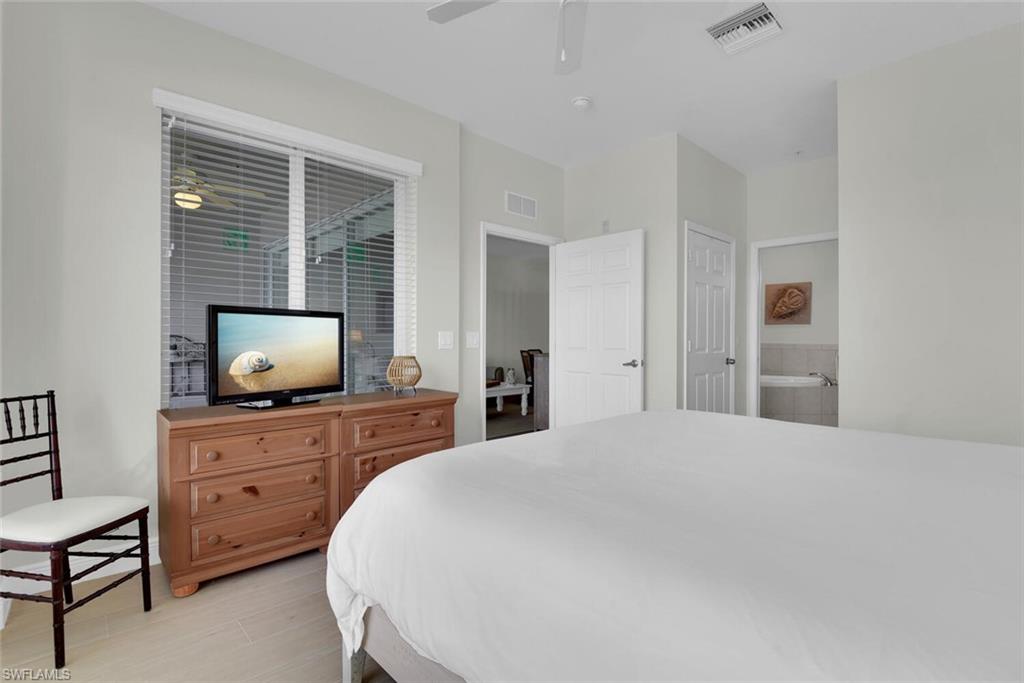 7925 Mahogany Run Lane, Unit 924 Naples, FL 34113 - Photo 19 of 40 a bedroom with a bed and a flat screen tv