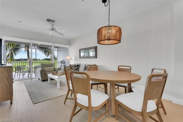 a dining room with wooden floor a chandelier a glass table and chairs