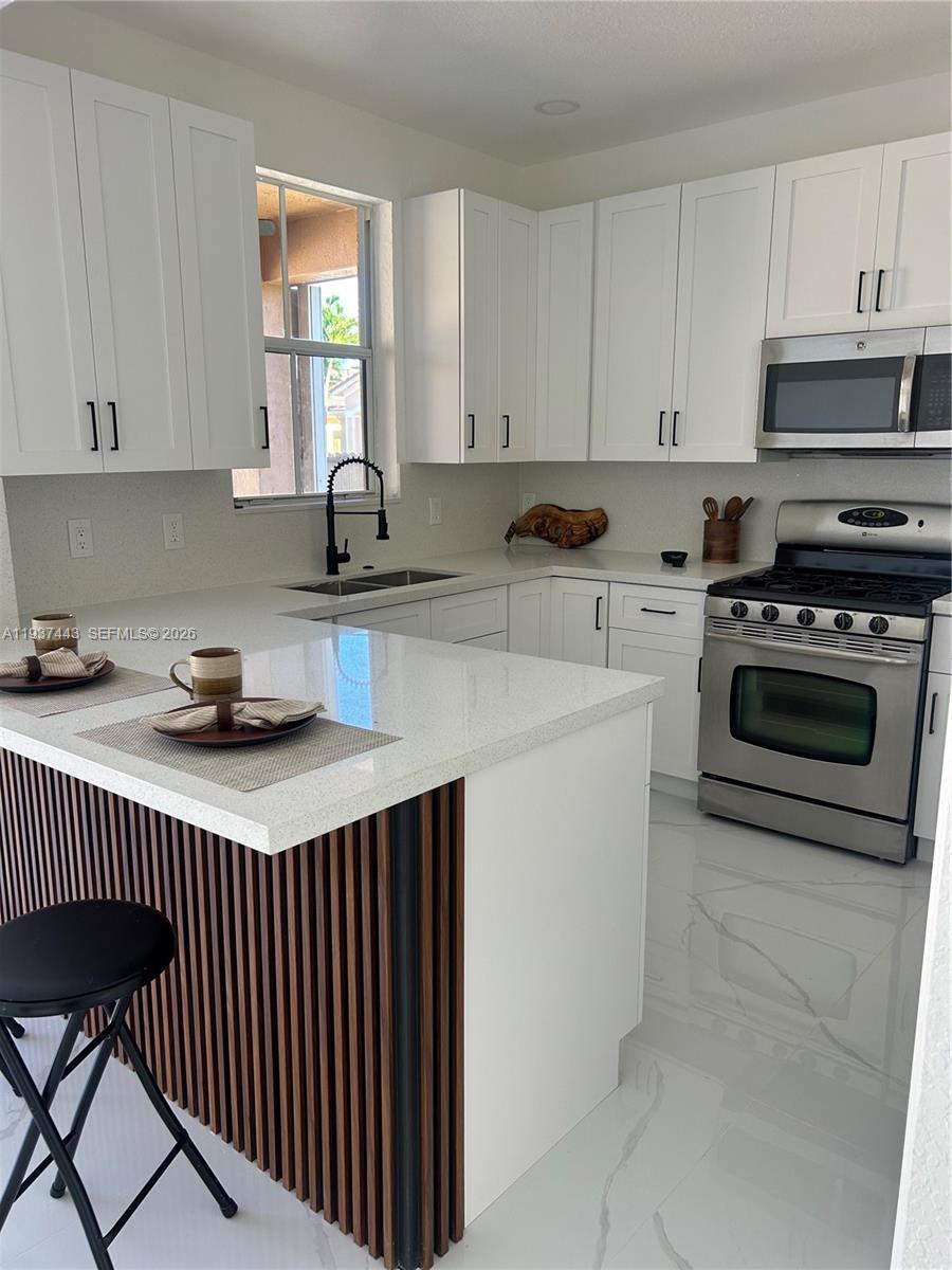7729 Northwest 194th Terrace Hialeah, FL 33015 - Photo 11 of 21 a kitchen with stainless steel appliances a stove a sink cabinets and a window