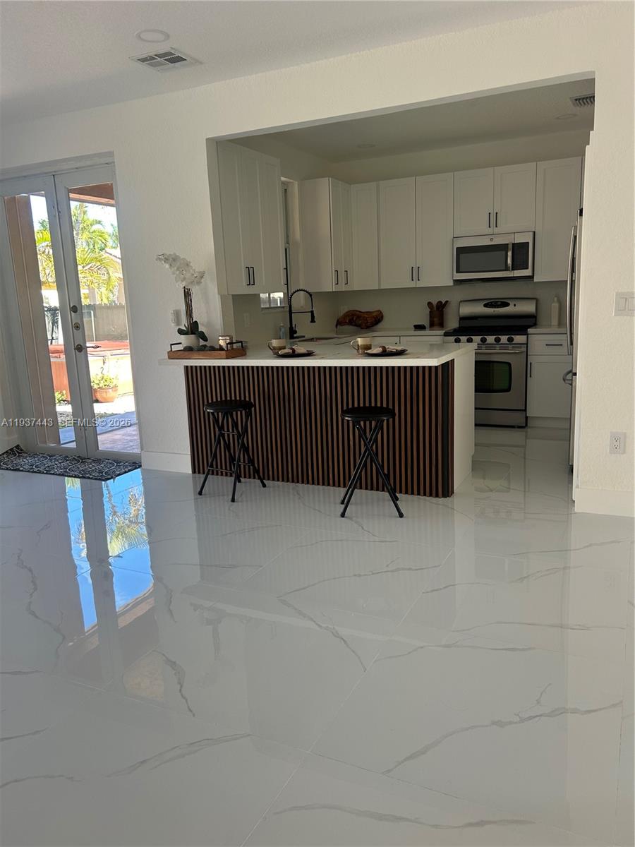 7729 Northwest 194th Terrace Hialeah, FL 33015 - Photo 12 of 21 a kitchen with stainless steel appliances a stove a sink and a microwave