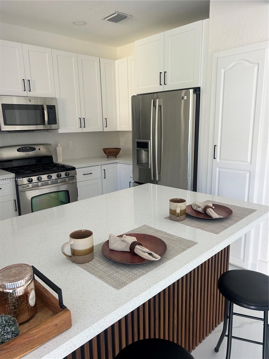 7729 Northwest 194th Terrace Hialeah, FL 33015 - Photo 14 of 21 a kitchen with a refrigerator and a stove top oven