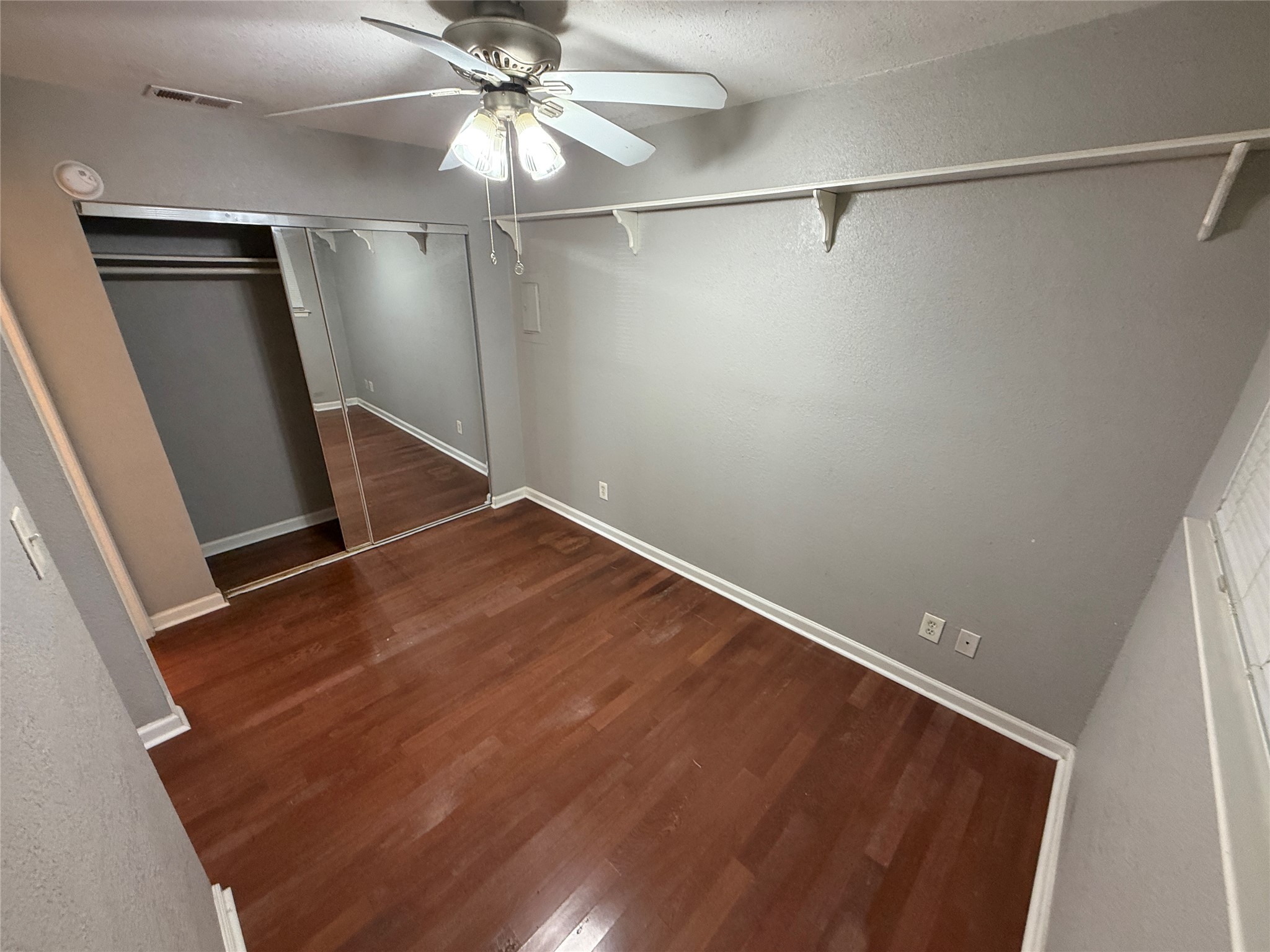 2500 Burleson Road, Unit 209 Austin, TX 78741 - Photo 7 of 15 Warm hardwood flooring runs throughout this versatile room featuring a mirrored closet and display shelving.