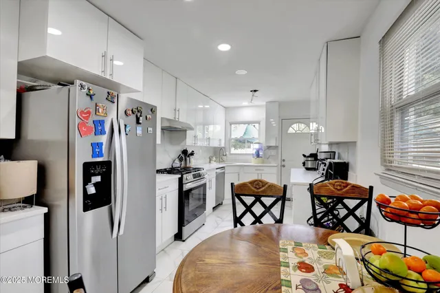 a kitchen with stainless steel appliances granite countertop a refrigerator and a dining table