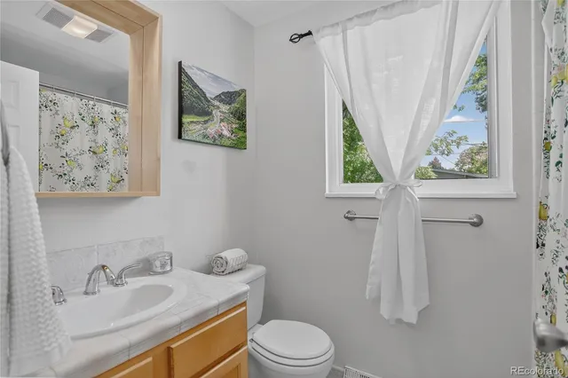 a bathroom with a granite countertop sink a toilet and a window