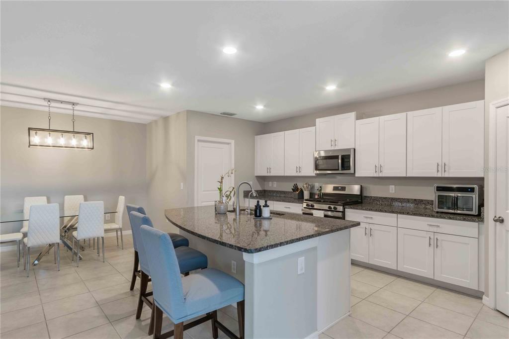 9440 Lemon Drop Loop Sun City Center, FL 33573 - Photo 18 of 55 a kitchen with white cabinets a sink and stove