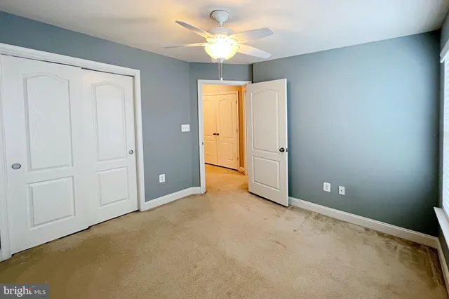 an empty room with closet and a chandelier fan