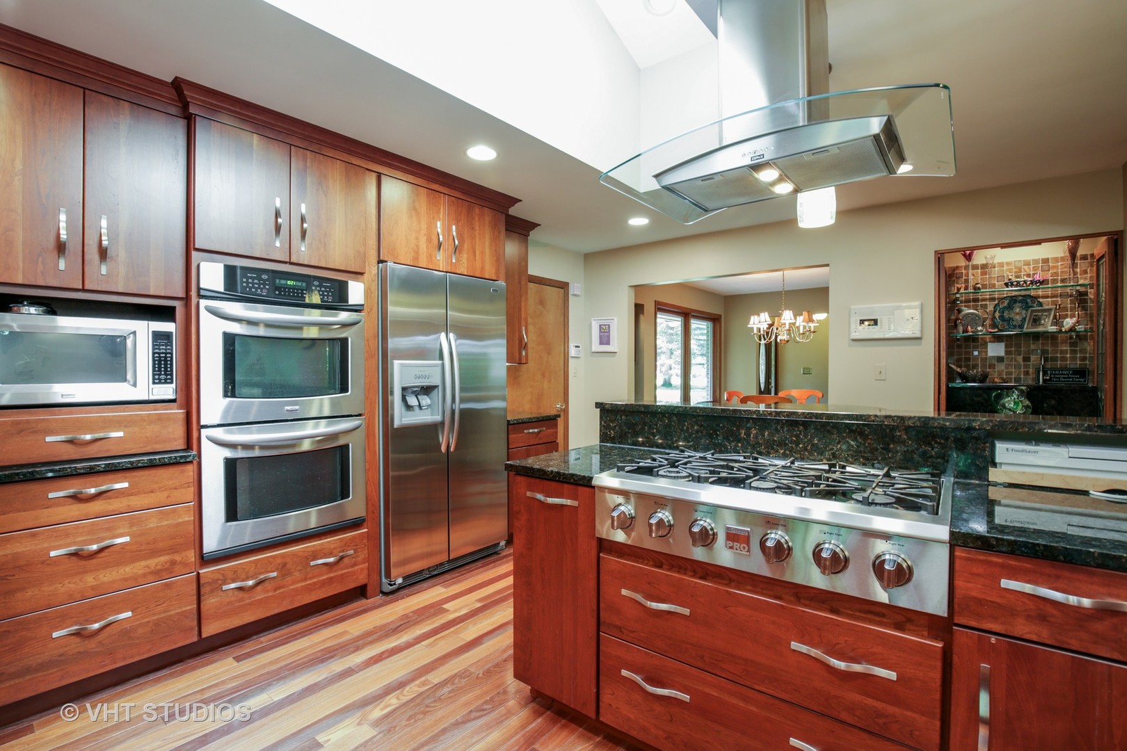 707 Hickory Road Woodstock, IL 60098 - Photo 3 of 16 a kitchen with stainless steel appliances granite countertop wooden cabinets and a stove top oven