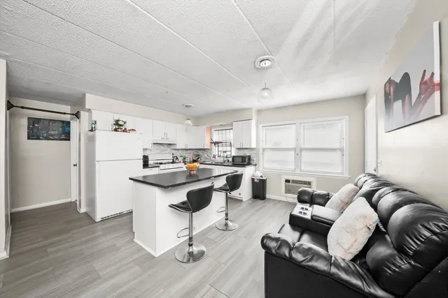a living room with furniture a rug kitchen view and a window