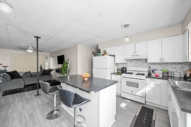 a kitchen with stainless steel appliances granite countertop a stove top oven a sink dishwasher and white cabinets with wooden floor