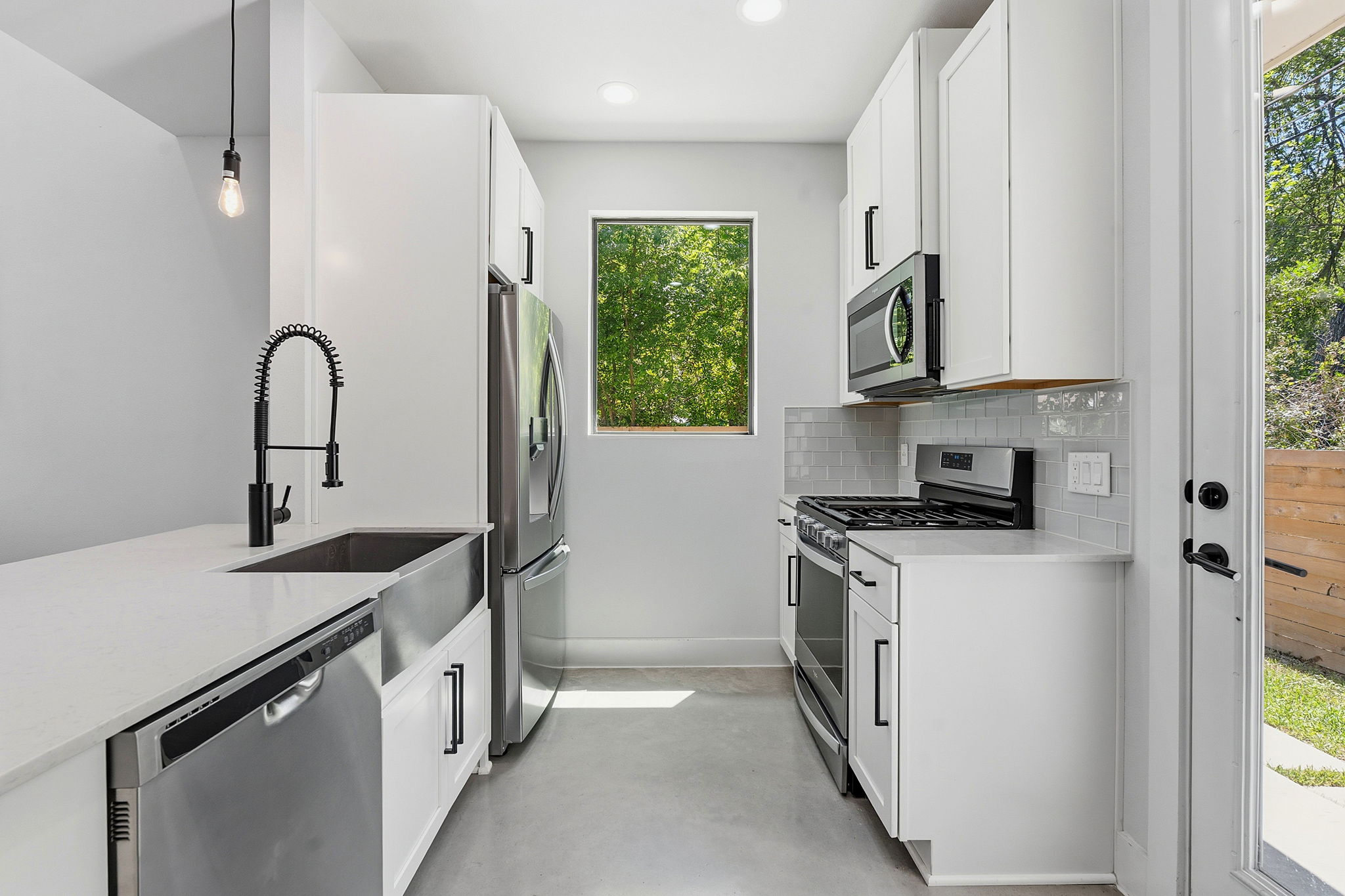 2935 Moss Street, Unit 2 Austin, TX 78722 - Photo 3 of 20 A streamlined kitchen offering bright white cabinetry, stainless appliances, and a window to nature.