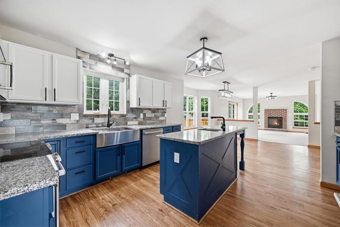 387 Blue Ridge Road Saylorsburg, PA 18353 - Photo 25 of 90 A well-appointed kitchen showcasing a spacious island and gleaming granite countertops, flowing into a comfortable living area with a classic brick fireplace.