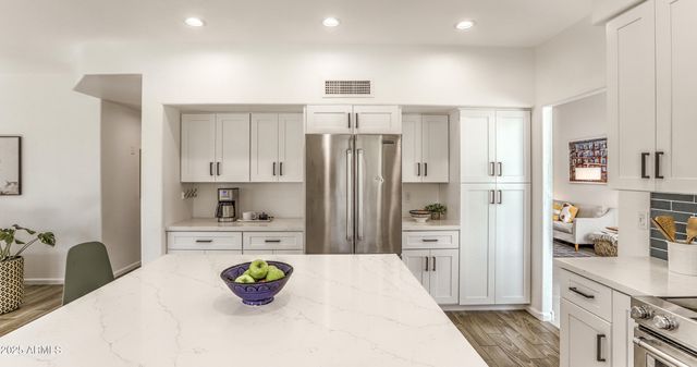 a kitchen with stainless steel appliances kitchen island granite countertop a refrigerator and a sink