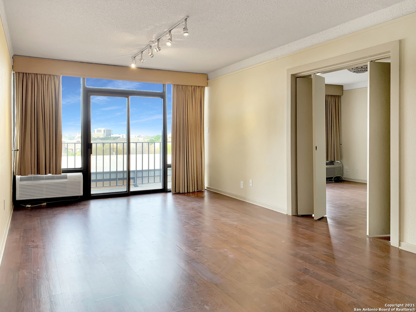 an empty room with wooden floor and windows